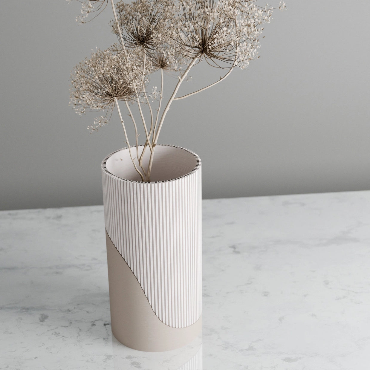 White ceramic vase with vertical ribbed texture and smooth beige base, holding dried Queen Anne's lace stems.