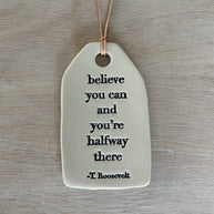 Decorative ceramic tag with inspirational quote on a wooden surface