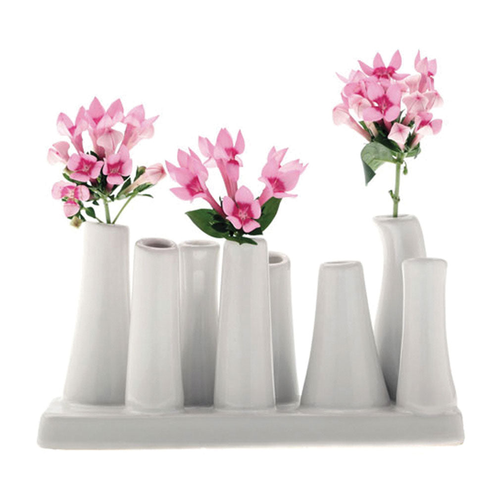 White ceramic multi-tube bud vase with eight cylindrical openings on rectangular base, displayed with pink flowers