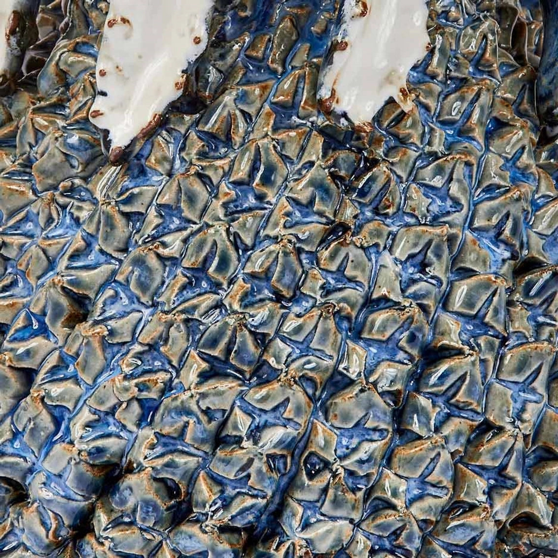 Ceramic art piece with deeply textured repeating leaf pattern in cobalt blue and bronze glazes creating dimensional surface