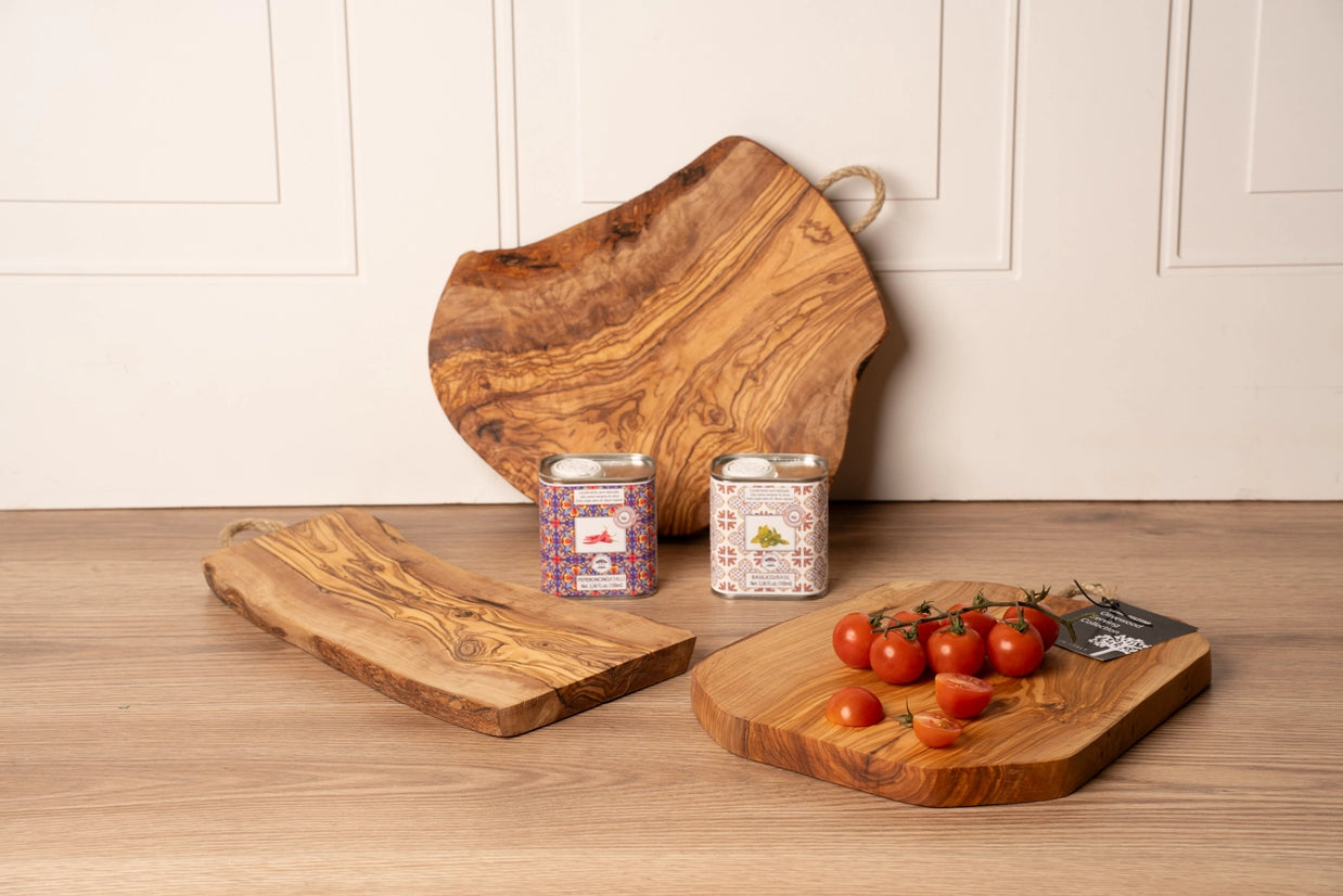 Olive wood cutting boards with natural live edge and swirling grain pattern displayed with cherry tomatoes and spice tins