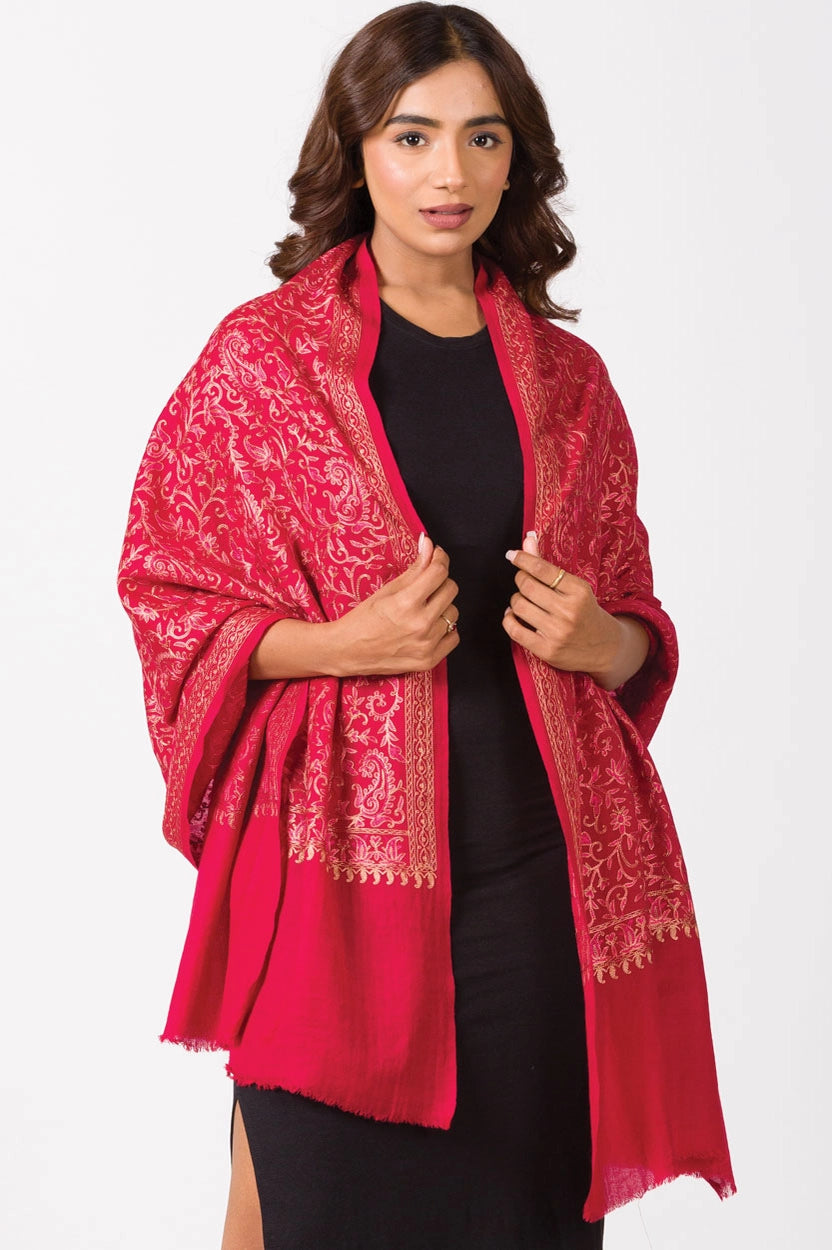 Crimson red pashmina shawl with gold embroidered floral paisley pattern and fringed edges draped over black dress