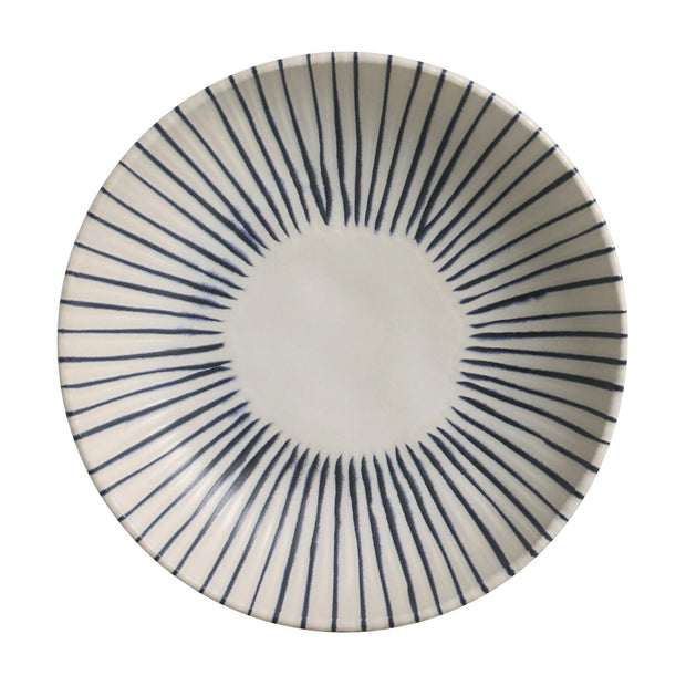 White stoneware salad bowl with navy blue radiating stripe pattern emanating from center in sunburst design