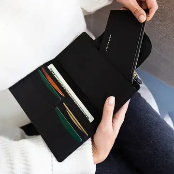 Black leather wallet with rainbow striped card slots held open by hands showing zippered compartment and multiple card pockets
