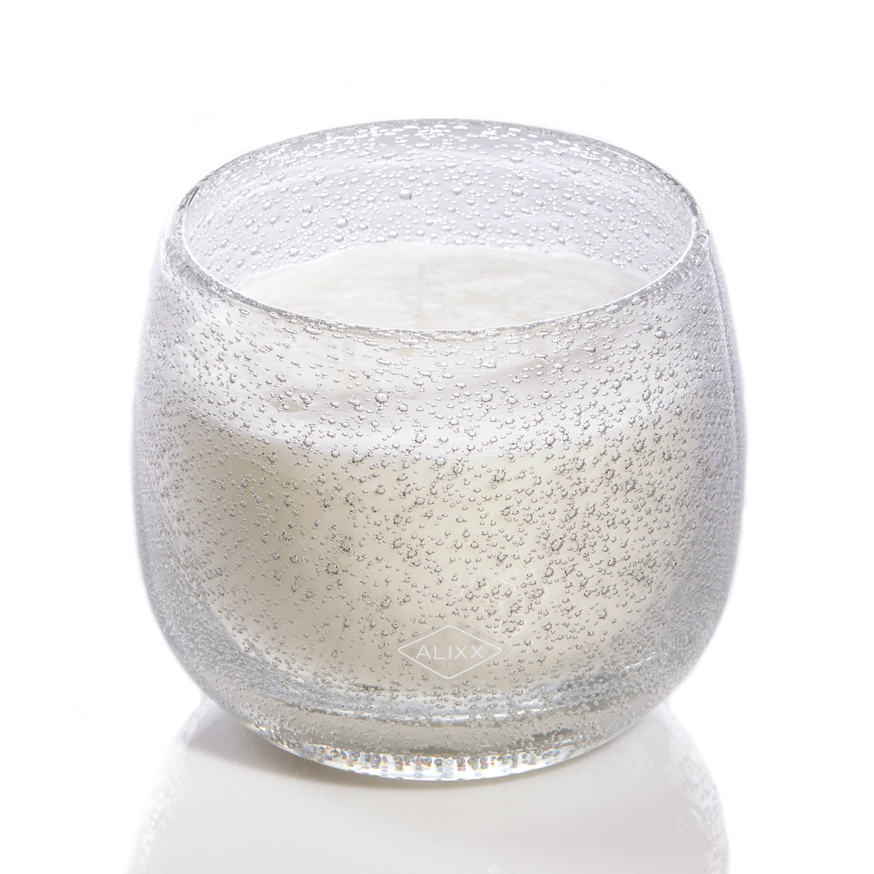 Clear glass candle with textured bubble pattern exterior, filled with white wax, rounded balloon-shaped vessel with ALIXX logo