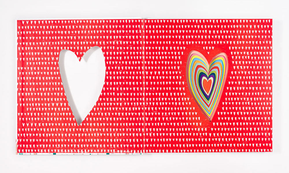 Red fabric with white heart pattern featuring white cutout heart and colorful concentric heart applique in rainbow stripes