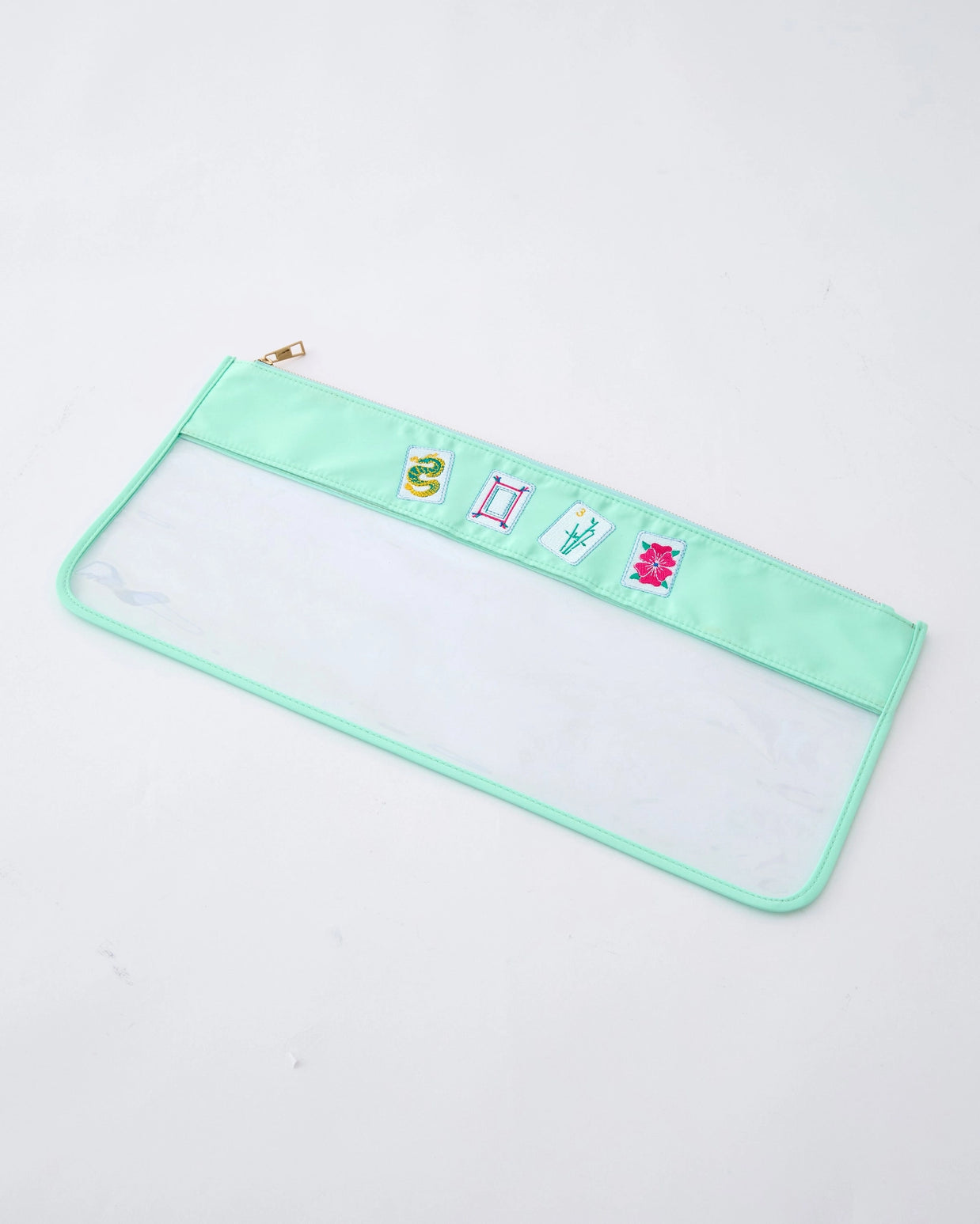 Clear vinyl pencil case with mint green trim and gold zipper featuring four embroidered patches of mahjong tiles