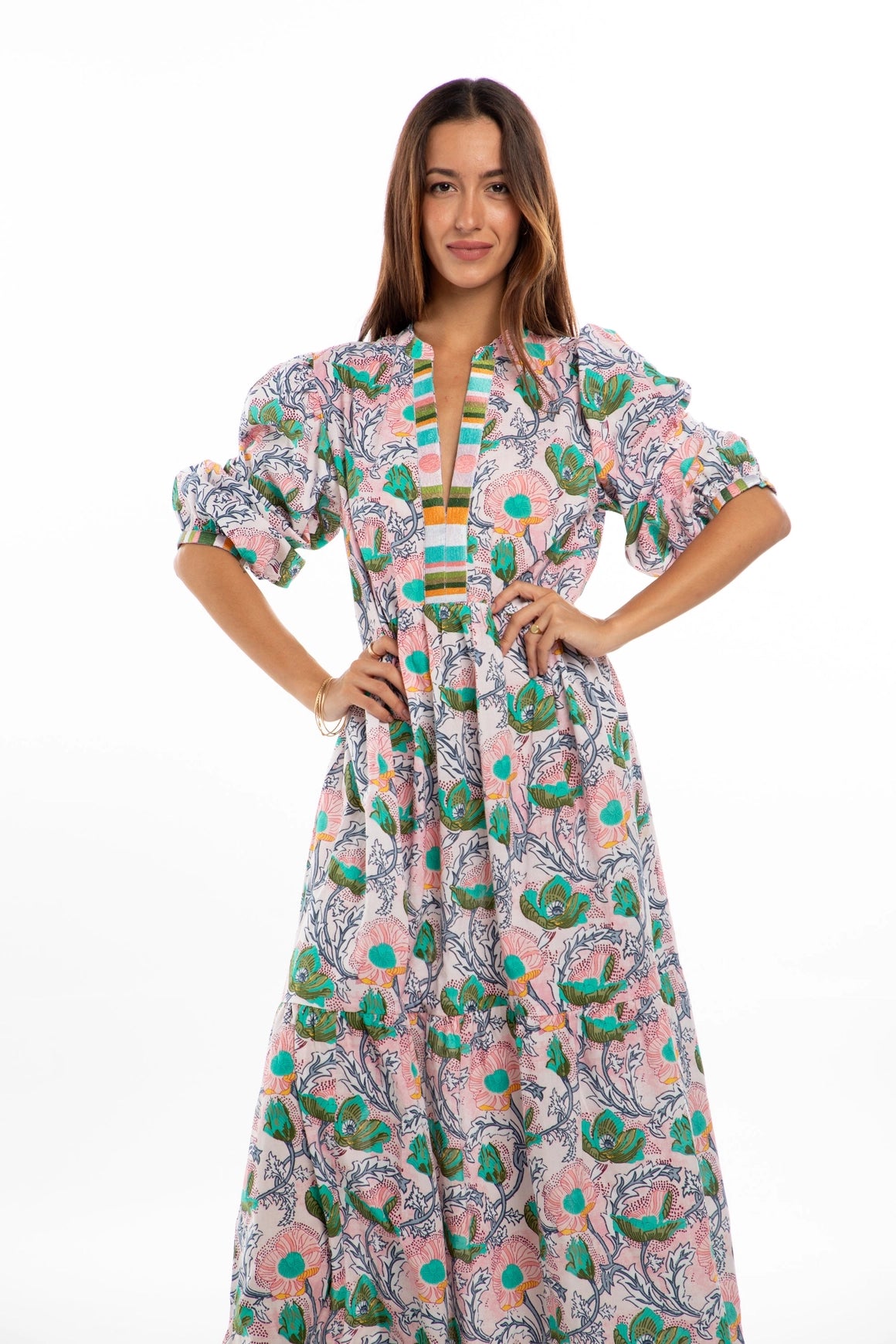 Cotton maxi dress with pink floral pattern, turquoise accents, puffed sleeves, striped trim, and V-neckline on white background