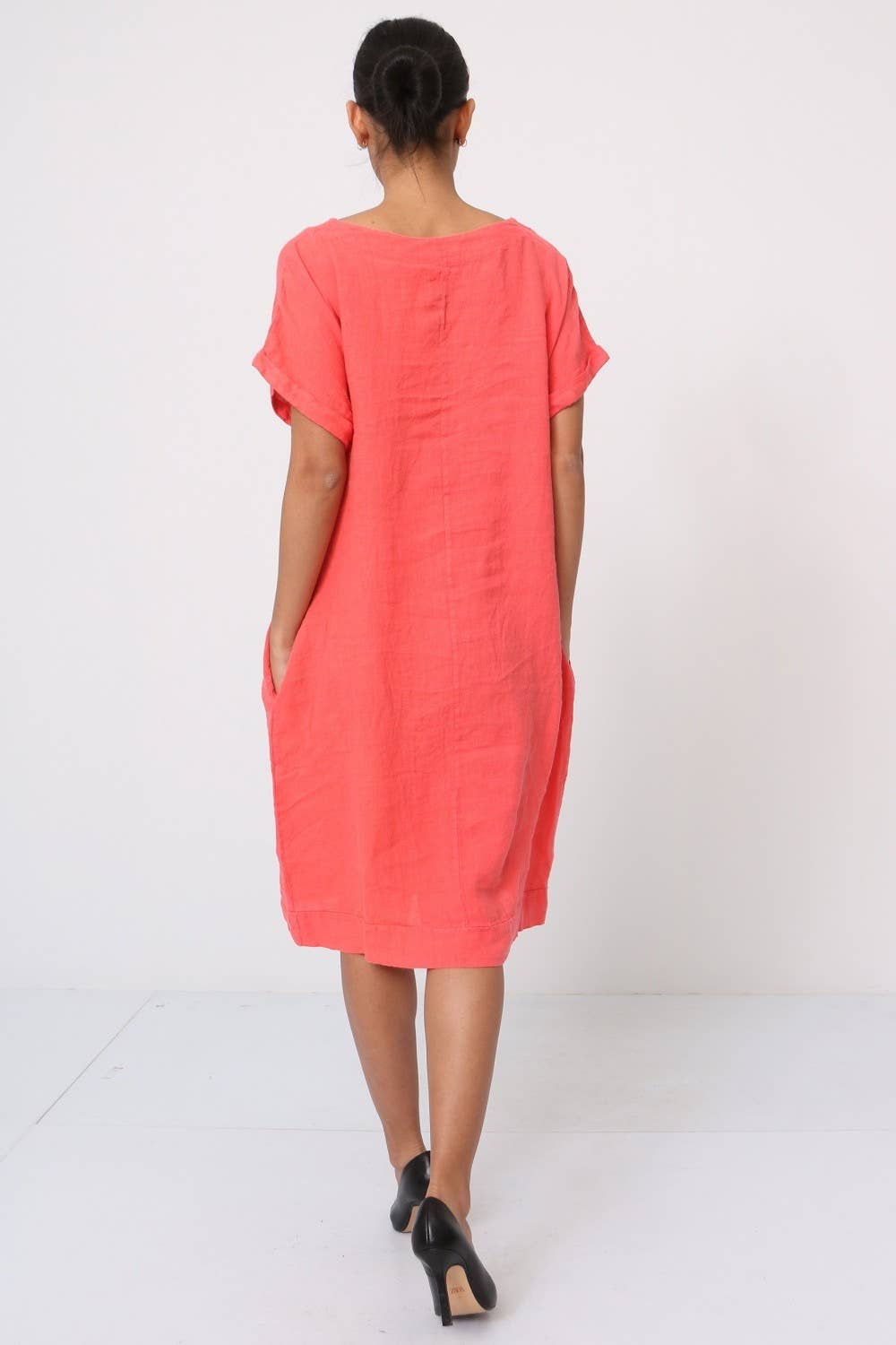 Coral linen shift dress with rolled short sleeves, boat neckline, and relaxed cocoon silhouette shown from back view