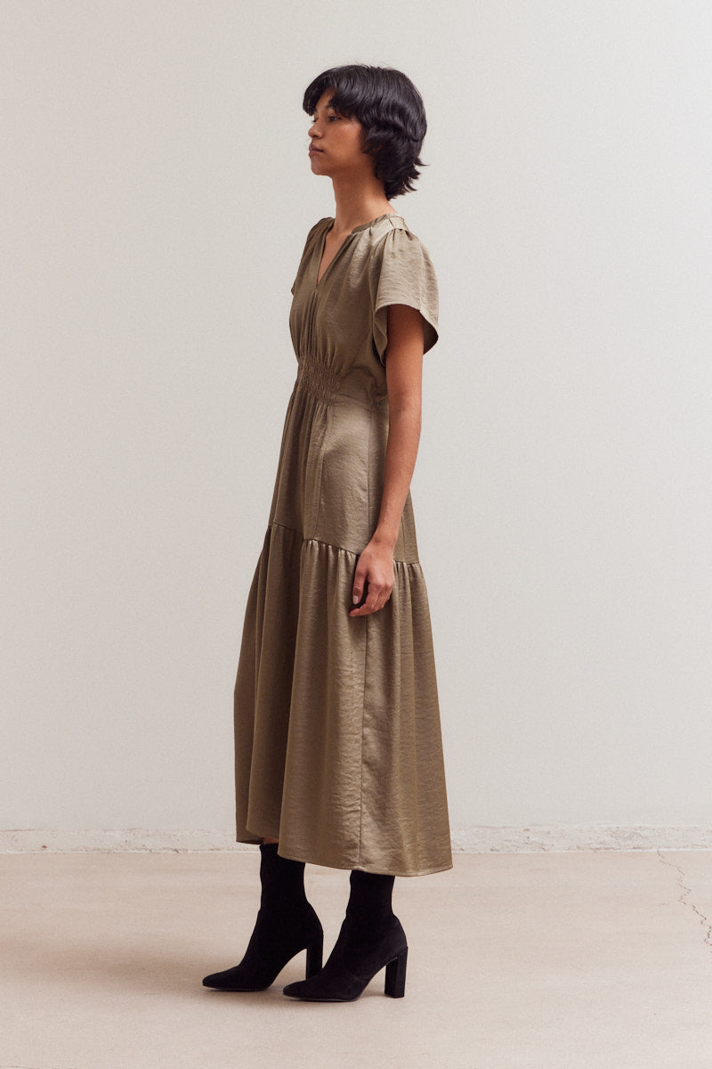 Olive green midi dress with shirred waist, V-neck, short sleeves, and tiered ruffle hem worn with black ankle boots