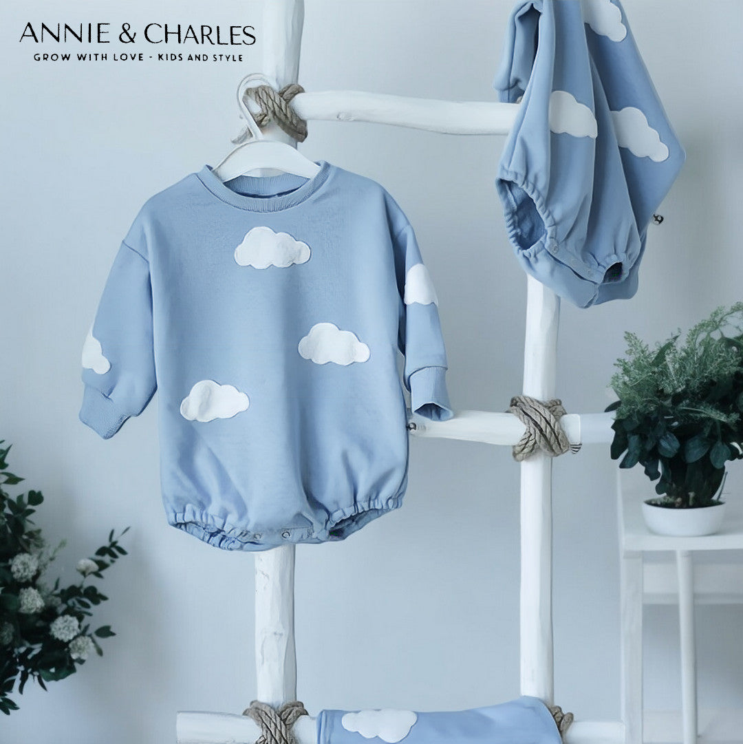 Sky blue cotton baby romper with white puffy cloud appliqués on chest and sleeves with ribbed cuffs and snap closure