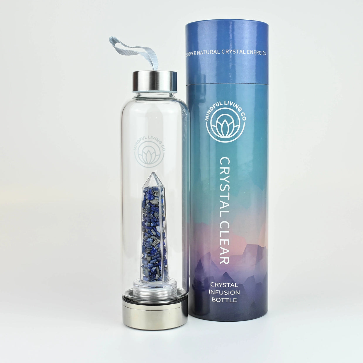 Clear glass water bottle with blue lapis lazuli crystals in center chamber, silver cap, and gradient blue-purple cylindrical packaging tube
