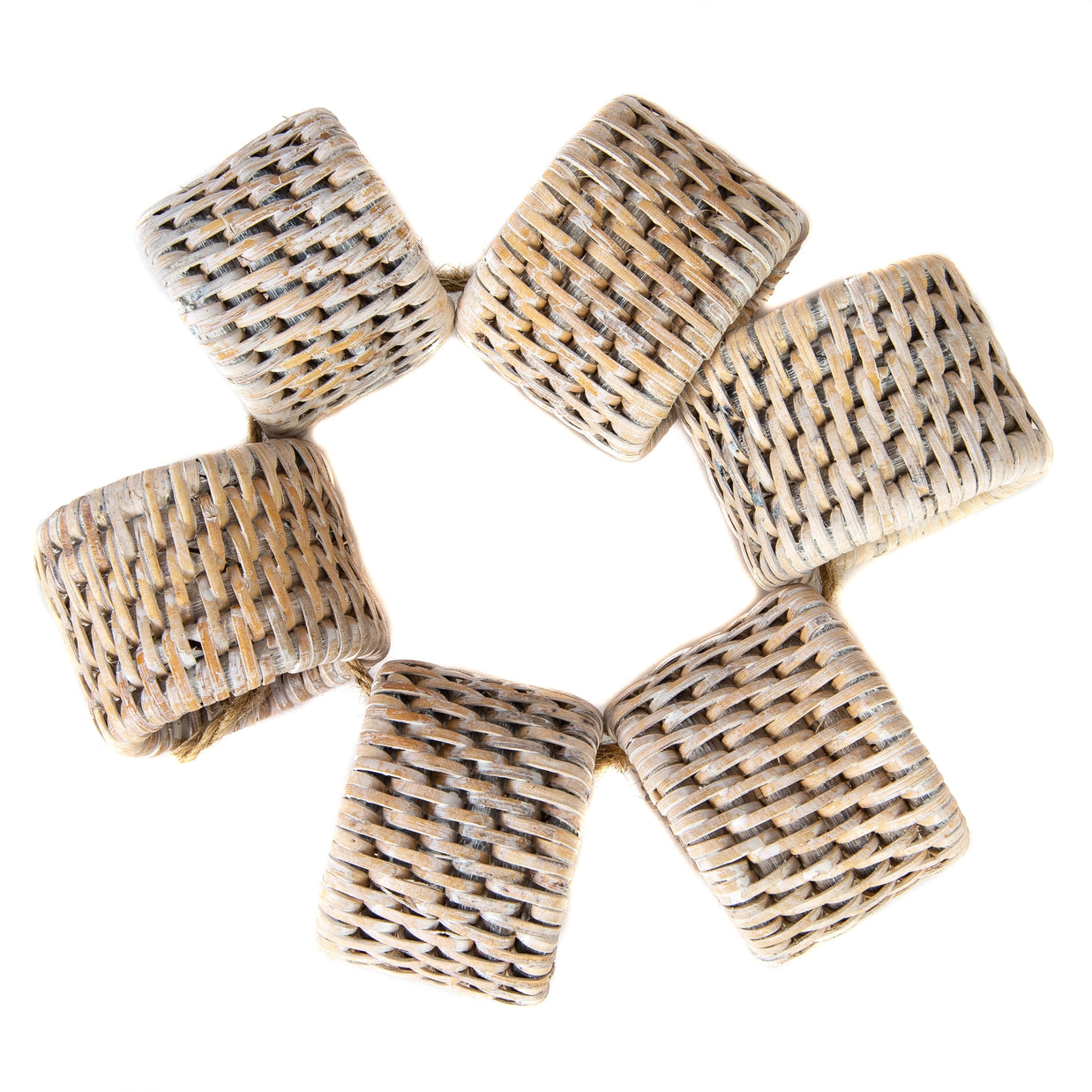 Set of six natural woven rattan napkin rings with oval shape and open lattice weave pattern in beige tones