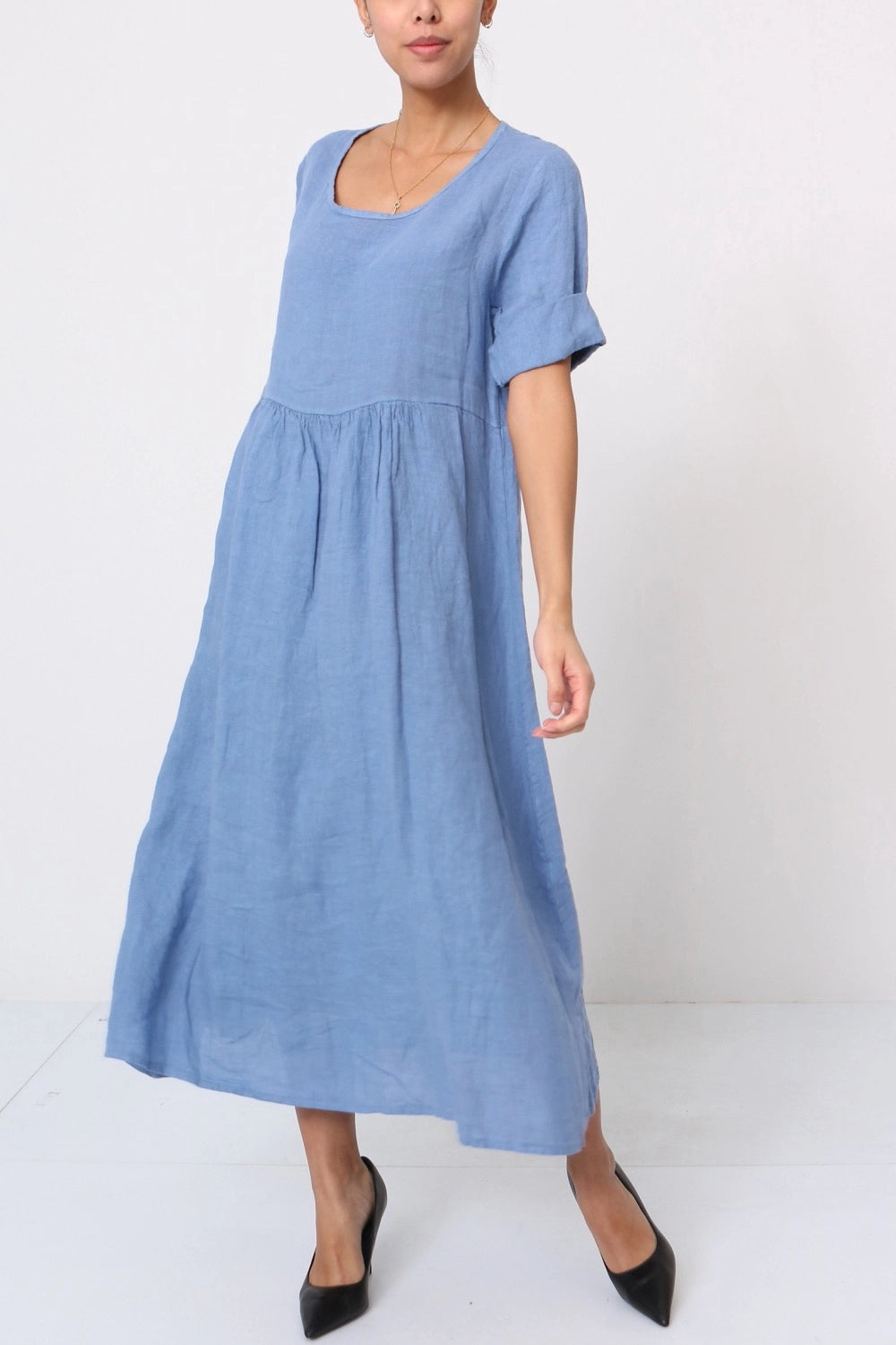 Periwinkle blue linen midi dress with gathered empire waist, rolled short sleeves, and scoop neckline on model