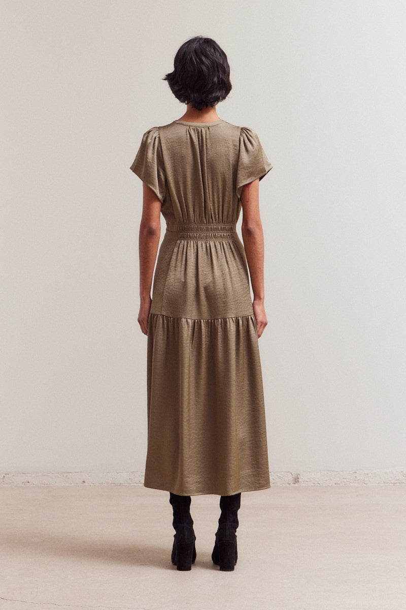 Taupe midi dress with gathered waist, puffed short sleeves, and tiered ruffle hem shown from back on model with black boots