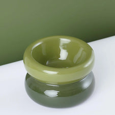 Glossy olive green ceramic bowl with smooth rounded edges and wide shallow interior on white surface