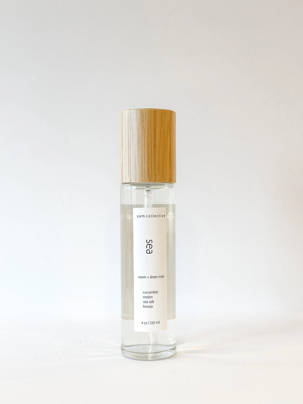 Clear glass spray bottle with bamboo cap, white label reading Sea room and linen mist with cucumber melon scent notes