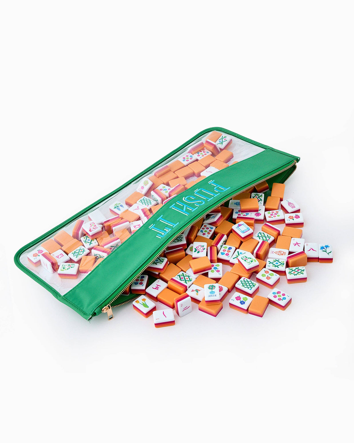 Mini mahjong set with colorful orange and white tiles with traditional symbols spilling from green vinyl zipper pouch