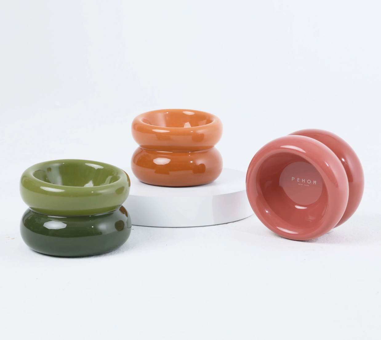 Glossy ceramic candle holders in olive green, terracotta orange, and dusty rose with chunky donut-shaped silhouettes