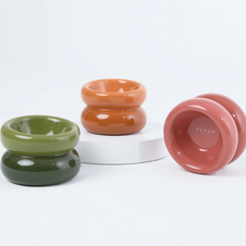 Glossy ceramic candle holders in olive green, terracotta orange, and dusty rose with chunky donut-shaped silhouettes