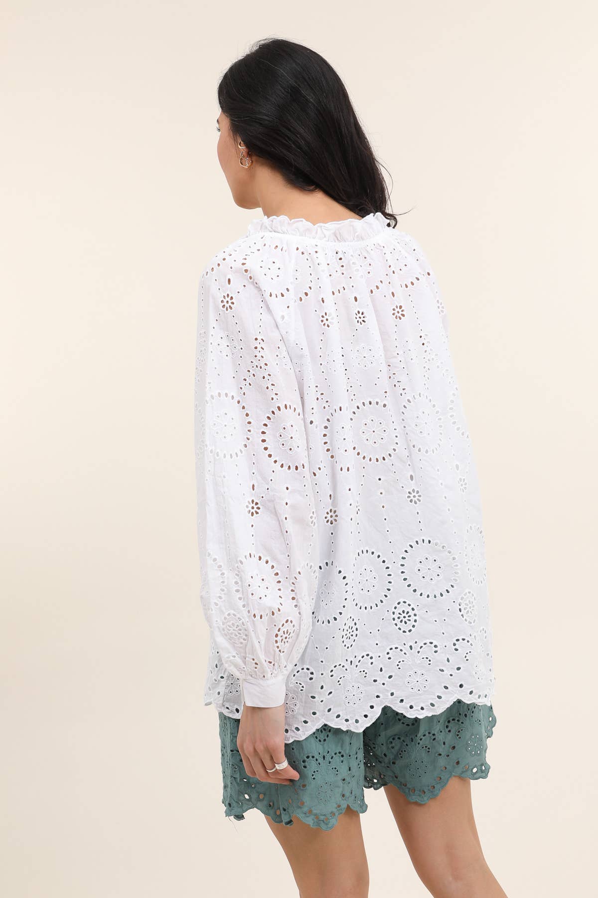 White cotton eyelet lace blouse with circular cutwork pattern, ruffled collar and scalloped hem, back view on model