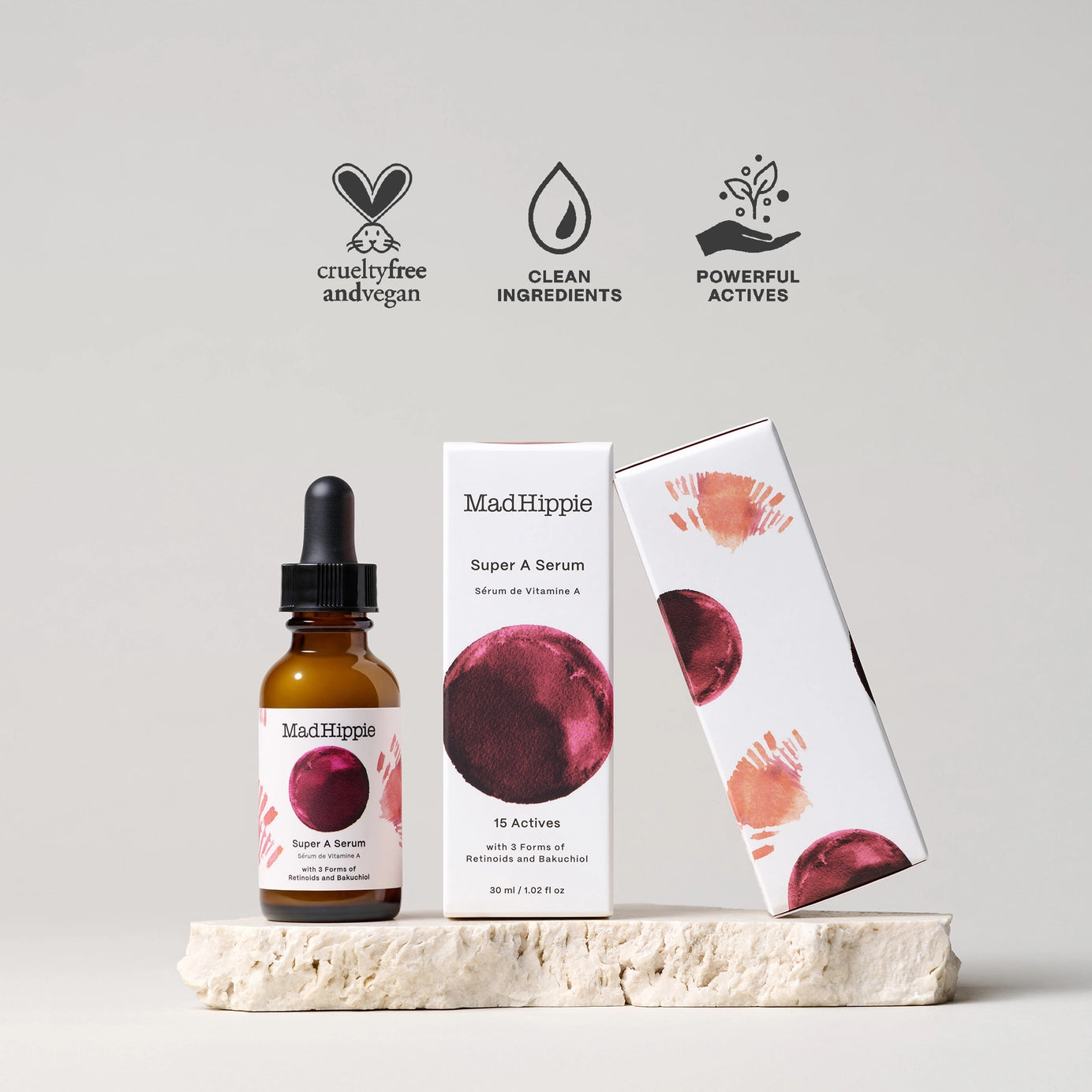 Amber glass dropper bottle and white box of MadHippie Super A Serum with burgundy plum graphic on textured stone display