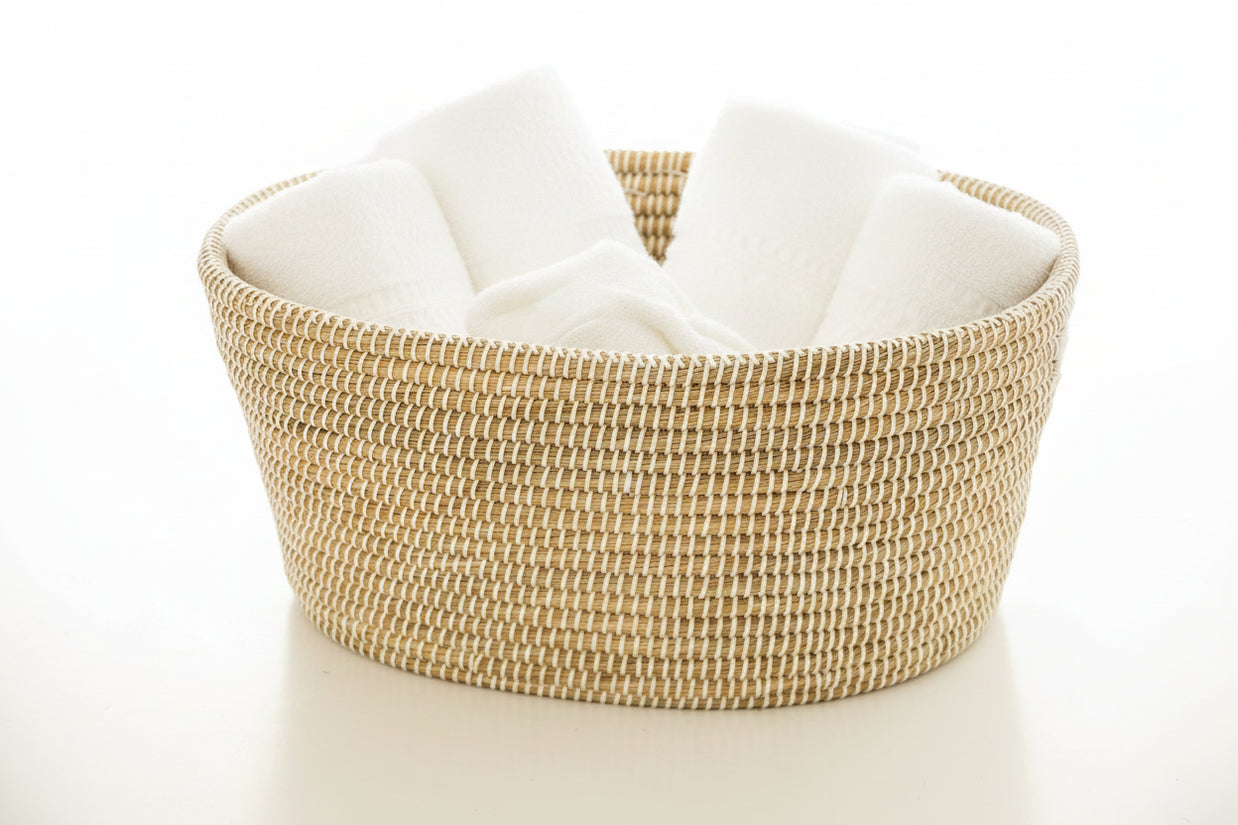 Handwoven round basket in natural tan and cream with tight coiled weave pattern and integrated side handles