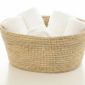 Handwoven round basket in natural tan and cream with tight coiled weave pattern and integrated side handles