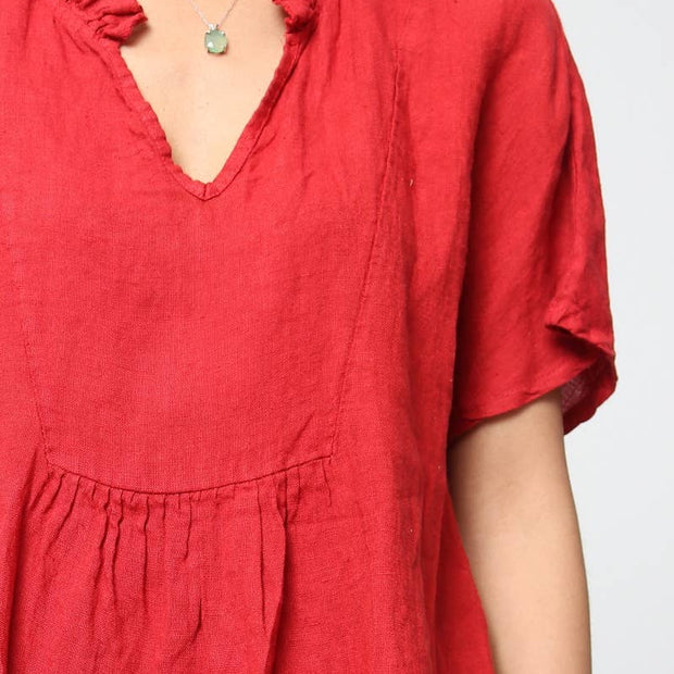 Coral red linen dress with ruffled v-neckline, gathered waist seam, short sleeves, and delicate mint green pendant necklace