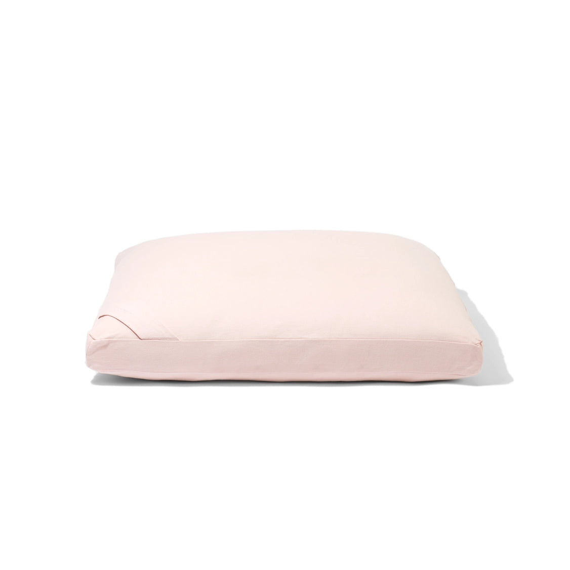 Rectangular pet bed cushion in pale blush pink fabric with piped edges and zippered gusset on white background