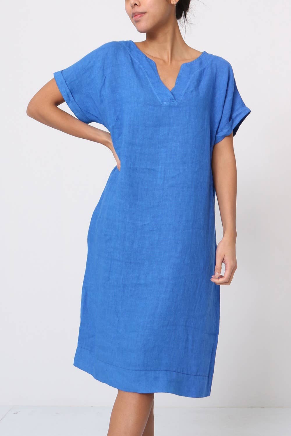 Cornflower blue linen shift dress with V-neck, rolled short sleeves, and relaxed knee-length silhouette in textured fabric