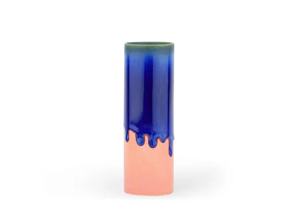 Cylindrical ceramic vase with cobalt blue drip glaze over coral pink base and olive green rim on white background