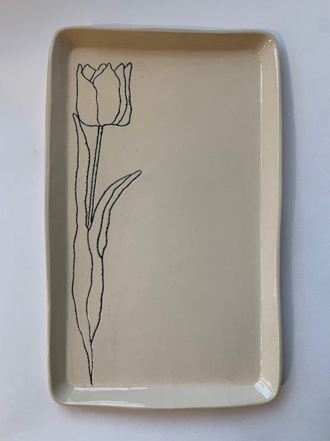 Cream ceramic rectangular tray with hand-drawn black line illustration of a single tulip flower with stem and leaves