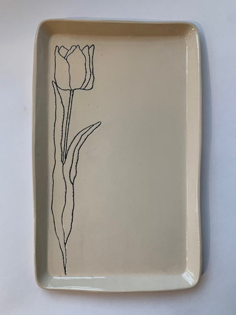 Cream ceramic rectangular tray with hand-drawn black line illustration of a single tulip flower with stem and leaves