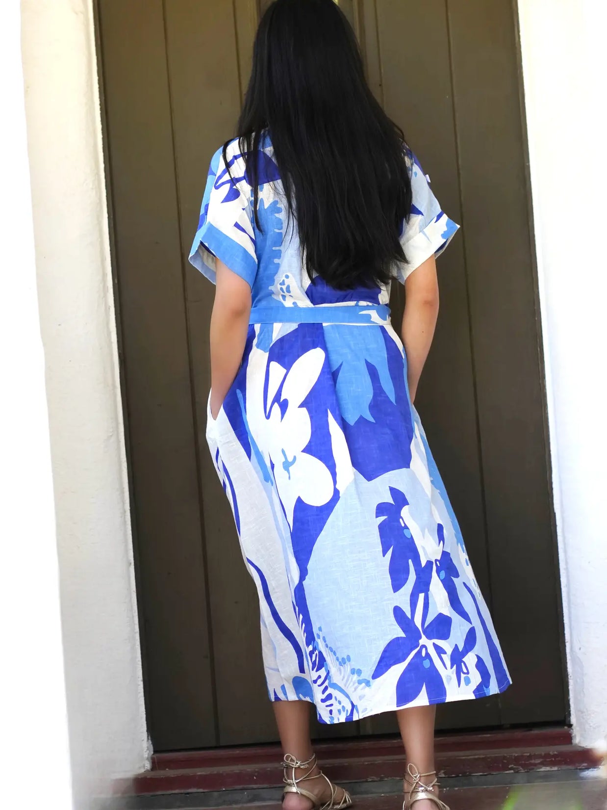 White midi dress with bold blue floral print featuring abstract botanical motifs, short sleeves, and belted waist