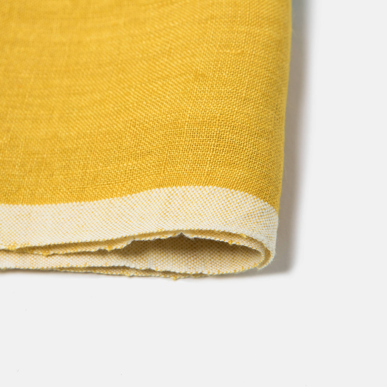 Golden yellow woven cotton fabric with white striped border hem, folded to show textured twill weave and raw edge detail