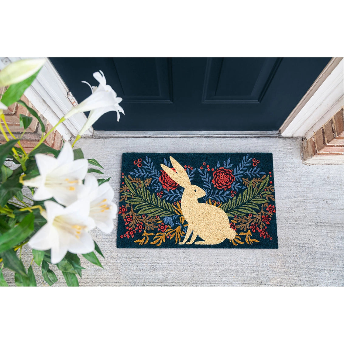 Coir doormat with golden rabbit silhouette surrounded by botanical wreath of ferns and coral flowers on navy background