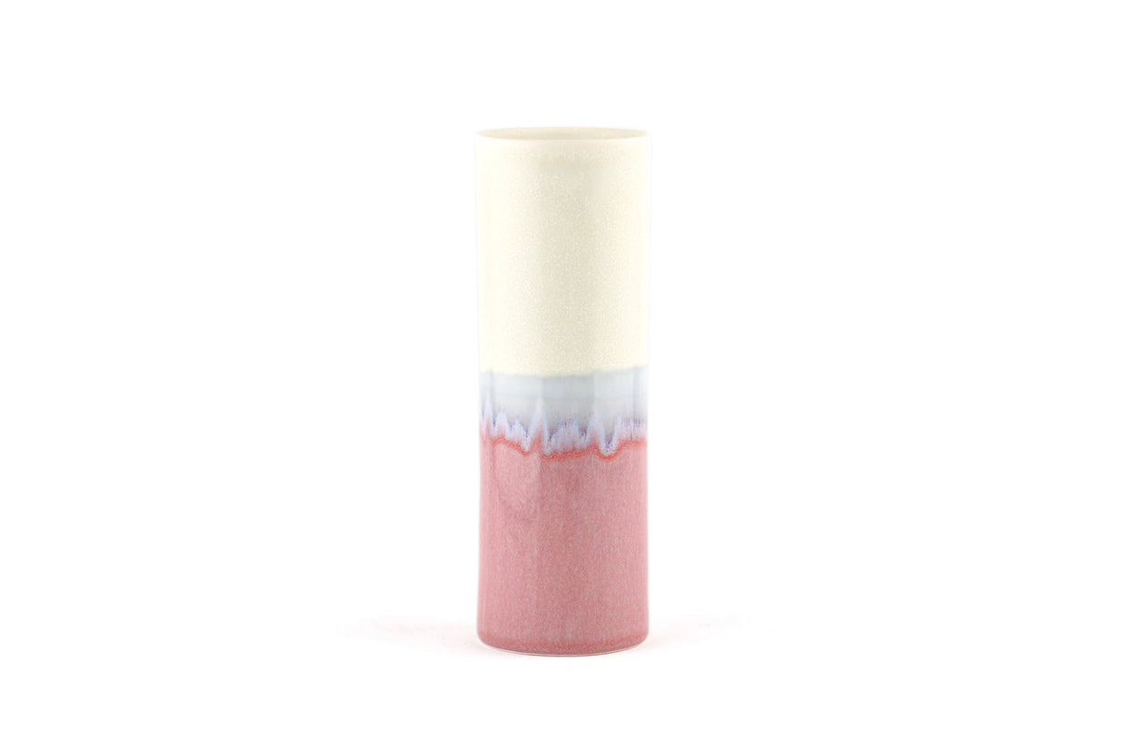 Cylindrical ceramic vase with cream upper half and coral pink lower half divided by organic dripped glaze pattern in blue-gray