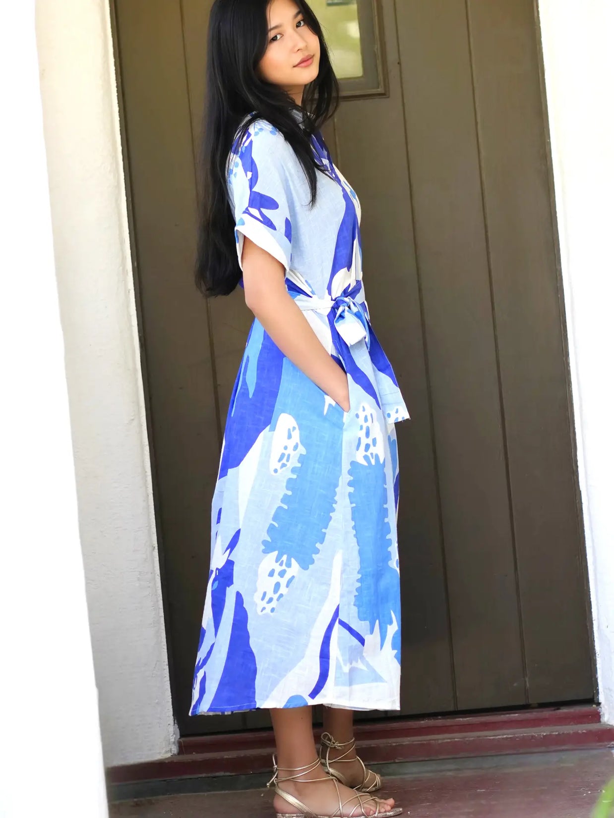 Light blue wrap dress with bold cobalt blue abstract floral print, short sleeves, and tie waist belt on model