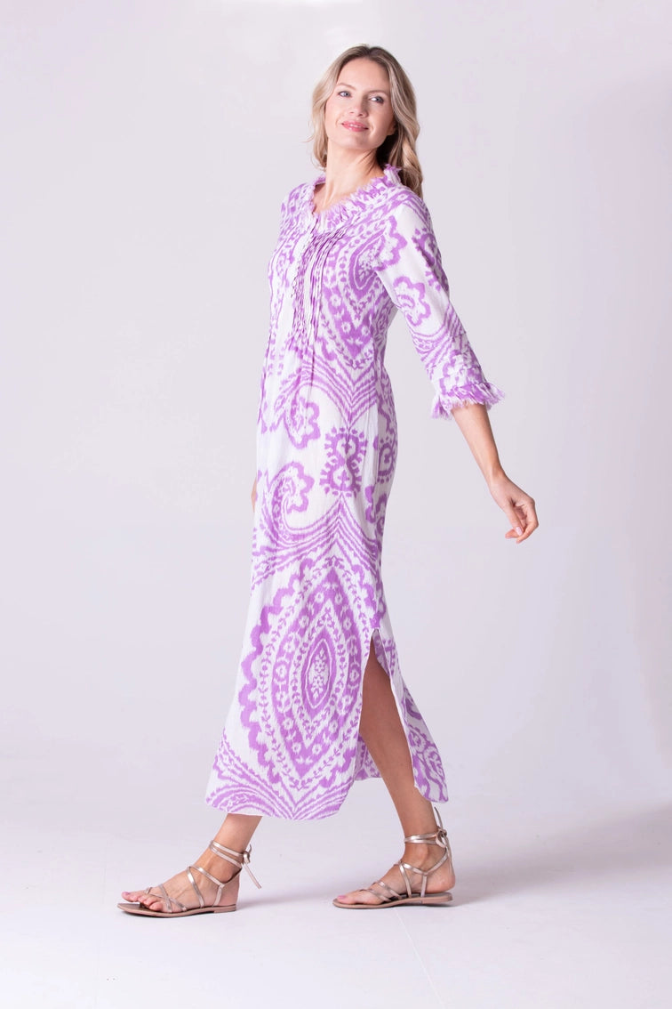 Flowing maxi caftan dress in purple and white medallion print with three-quarter sleeves, side slit, and tassel neckline