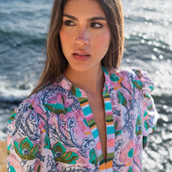 Cotton kimono robe in lavender with oversized pink and teal floral print and striped trim detail at ocean backdrop