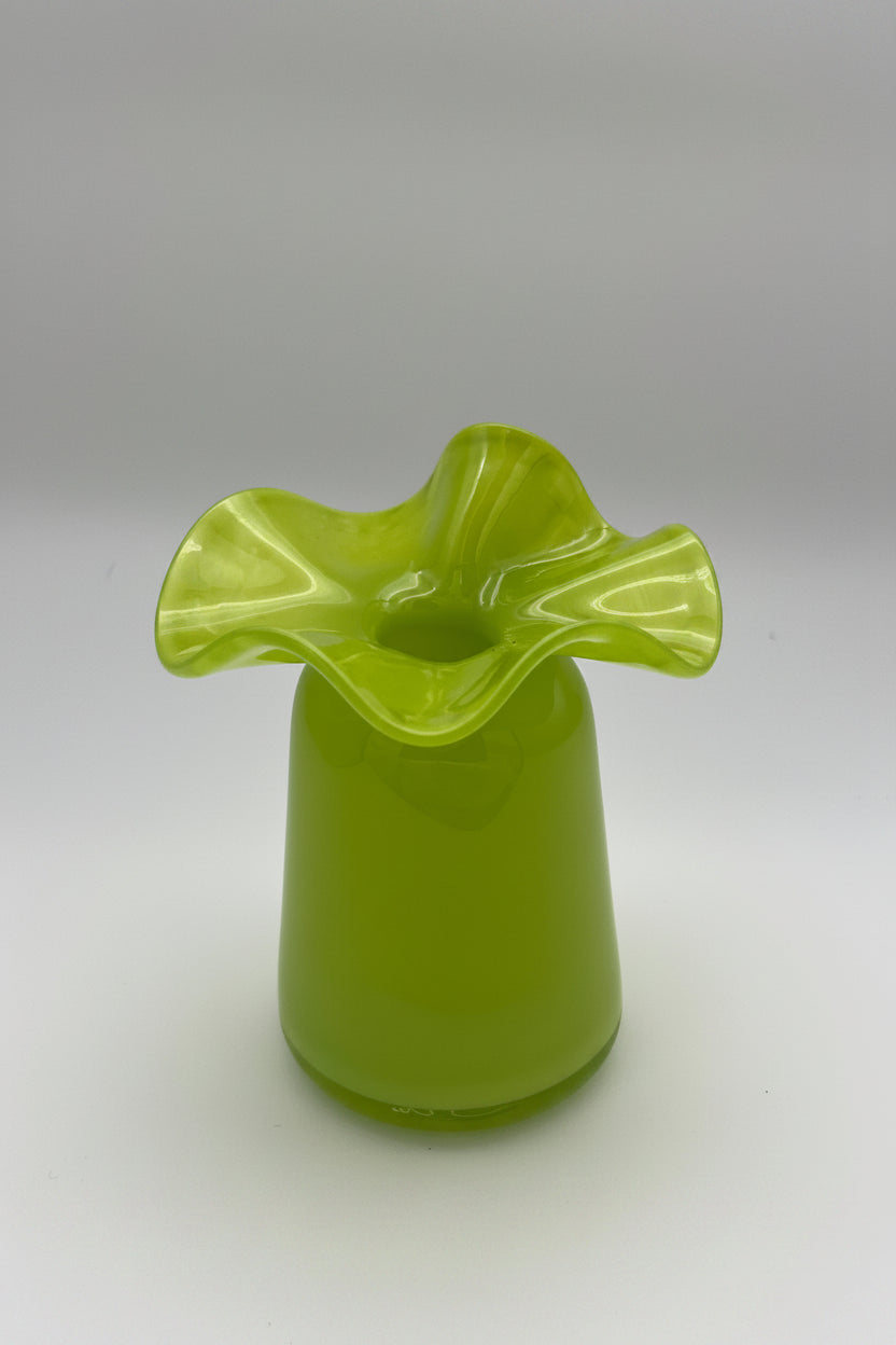 Chartreuse green art glass vase with ruffled four-petal rim and smooth cylindrical base on gray background