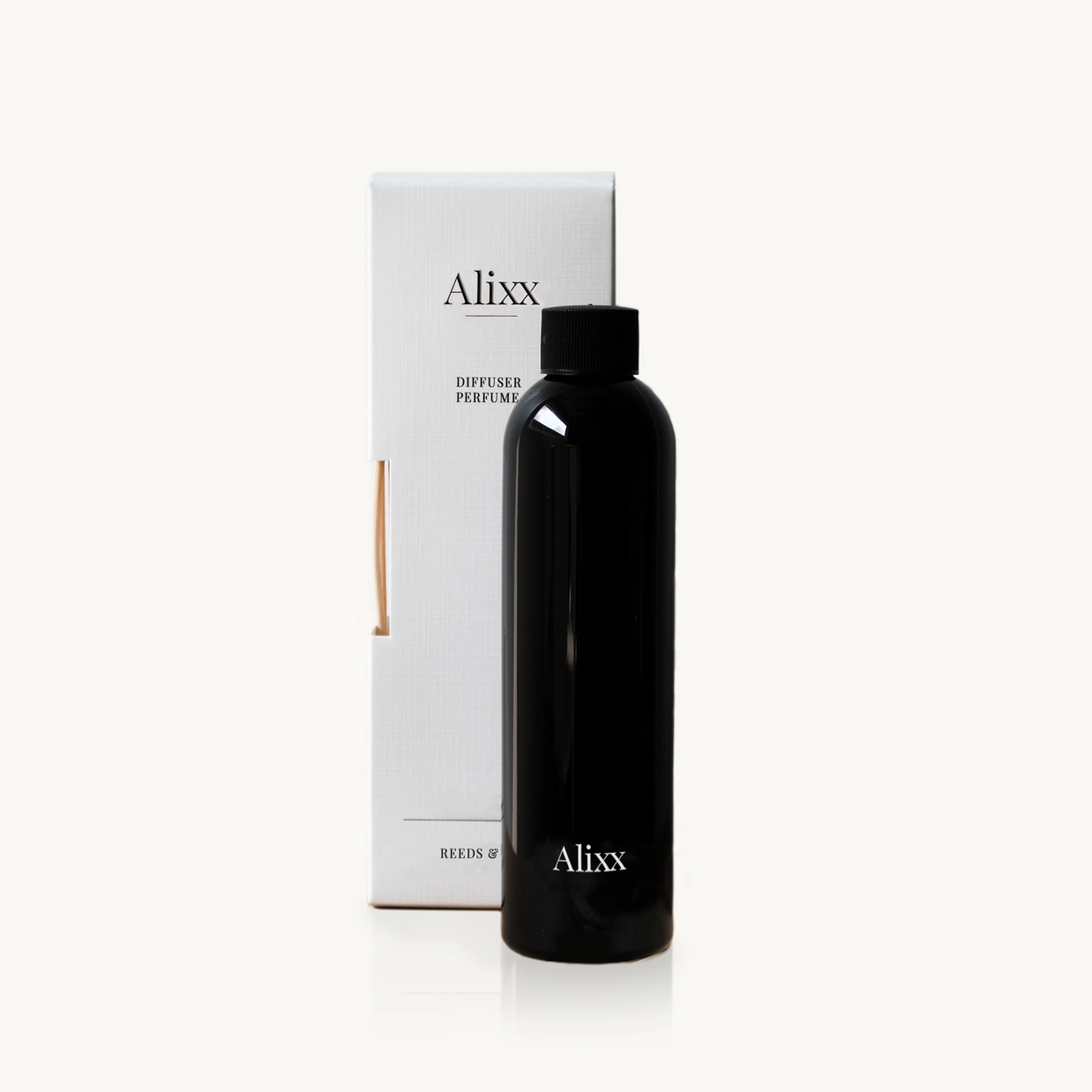 Glossy black bottle of Alixx diffuser perfume with black cap beside white minimalist box packaging with reed stick visible