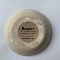 Bottom view of cream ceramic dish with ribbed texture and round kraft label reading Rosemary for remembrance friendship and love