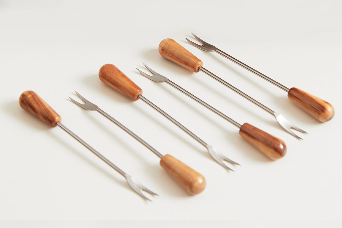 Set of five stainless steel cocktail forks with polished wooden handles in varying honey to rich brown tones, arranged diagonally.
