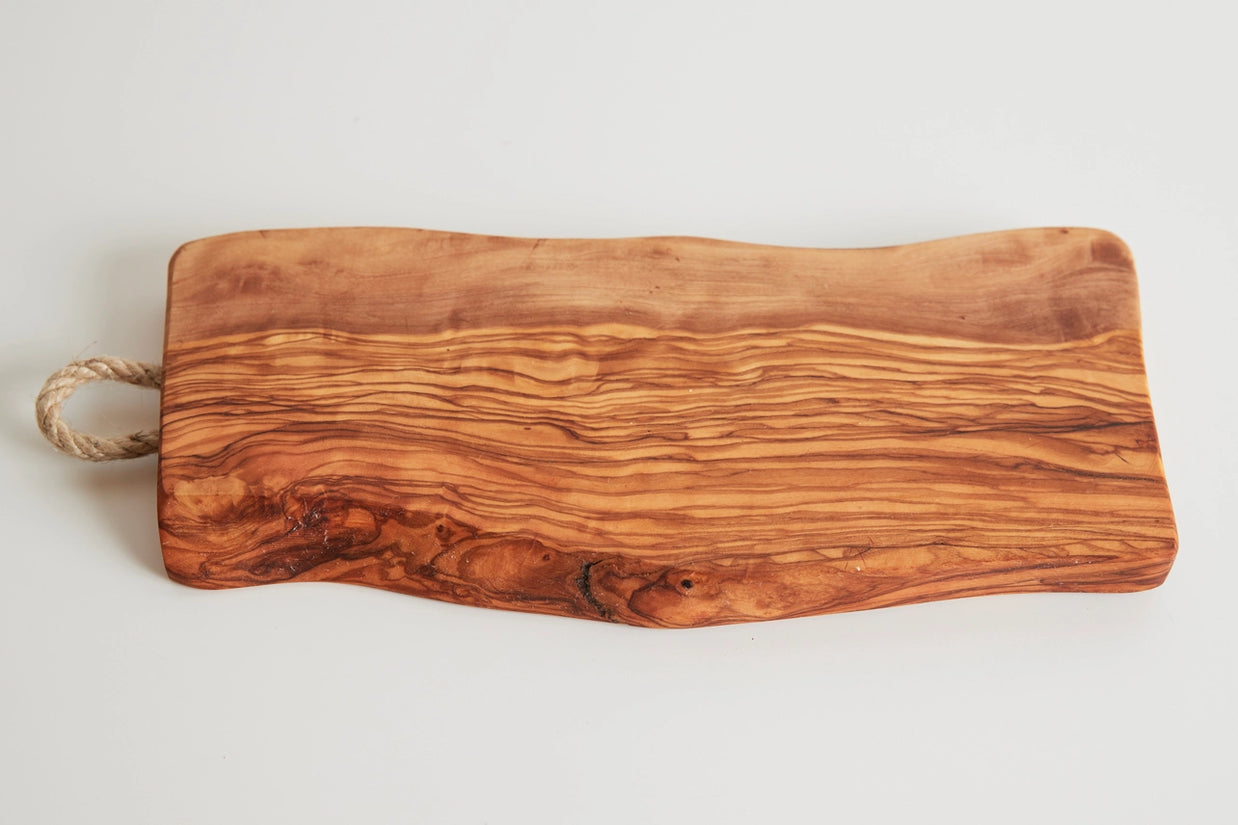 Rectangular olive wood cutting board with natural wavy grain patterns, live edge, and rope handle on left side