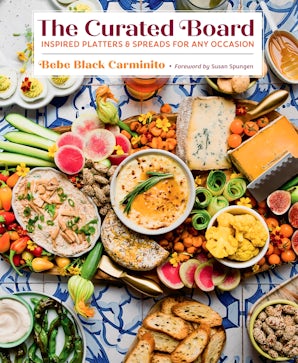 Overhead view of artfully arranged cheese and charcuterie board with fresh fruits, crackers, and spreads on blue-patterned tile