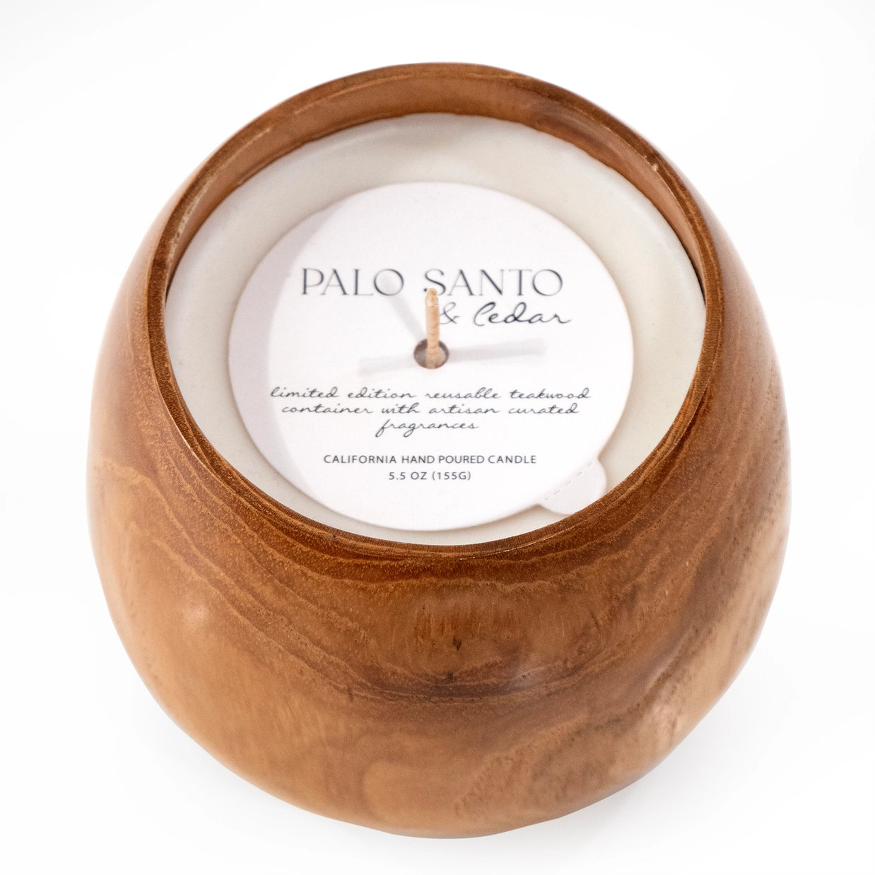 Palo Santo and Cedar scented candle in round carved teakwood container with white wax and wooden wick, top view