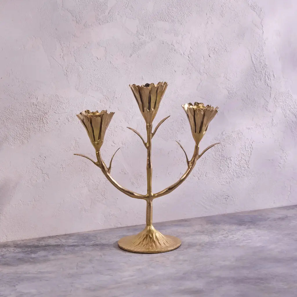 Brass three-arm candelabra with branching stems and tulip-shaped candle holders on textured round base
