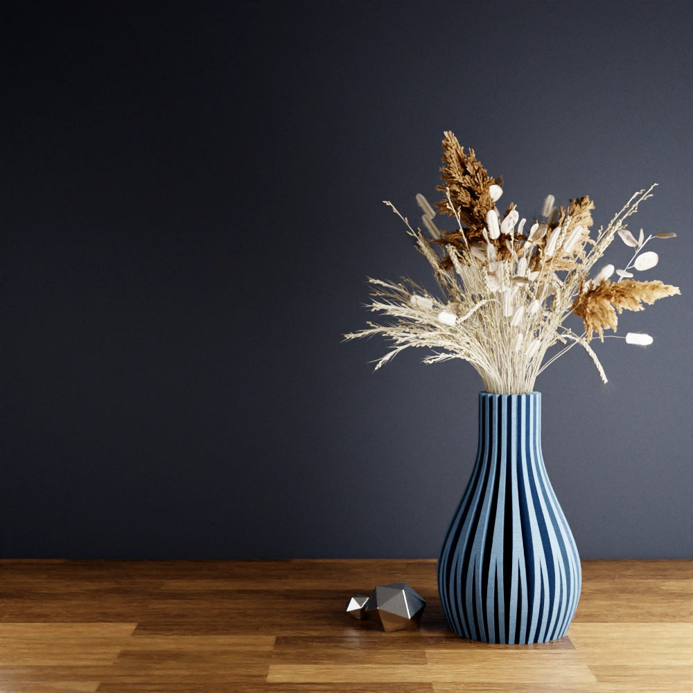 Navy blue ribbed ceramic vase with vertical ridges holding dried wheat, pampas grass, and white botanical arrangement
